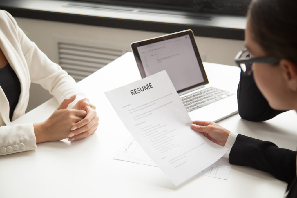 Company CEO and HR manager reading applicant resume or cv while employee waiting for questions, discussion and result during recruitment process in office. Concept of hiring, employment. Close up view